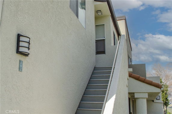 View of a house exterior with stairs leading to an upper floor entrance.