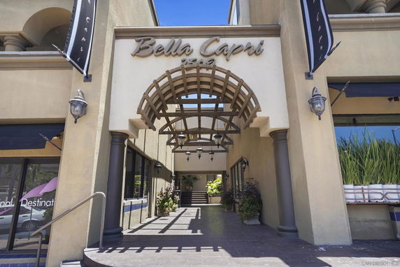 Front view of a building entrance with arched signage and a covered walkway.