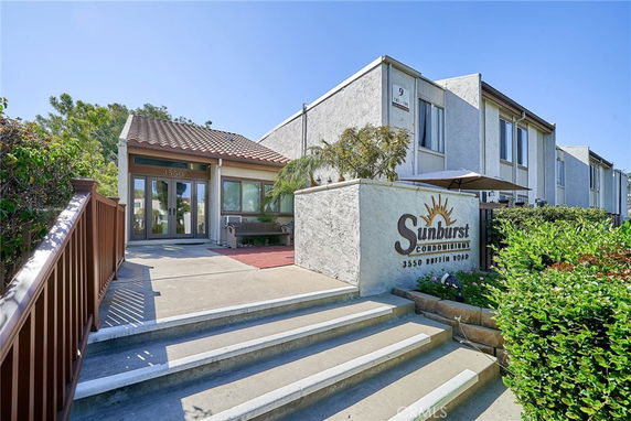 Front view of a condominium entrance with a pathway and steps leading to the main door.