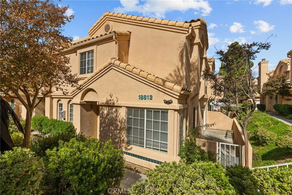 Front view of a two-story house with a light brown exterior and tiled roof.