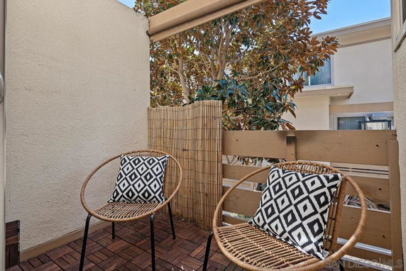 Small balcony area with two wicker chairs and decorative pillows.
