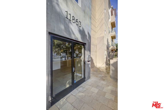 Front view of a modern building entrance with large glass doors and a visible address number above.