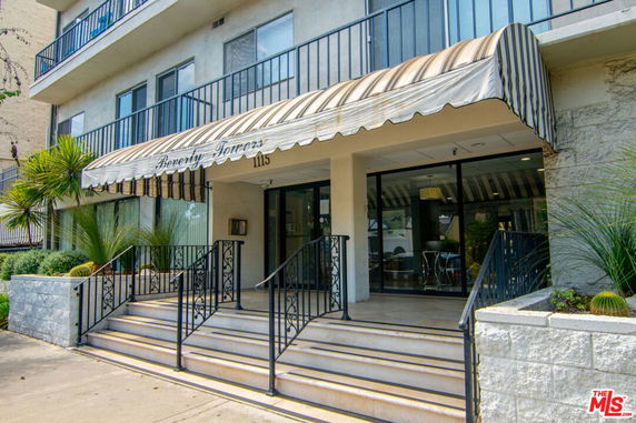 Front view of a multi-story building with entrance steps and awning.