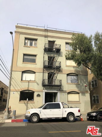 Front view of a multi-story apartment building with an exterior fire escape.