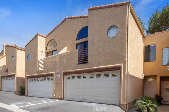 Front view of a multi-story house with double garage doors and circular windows.
