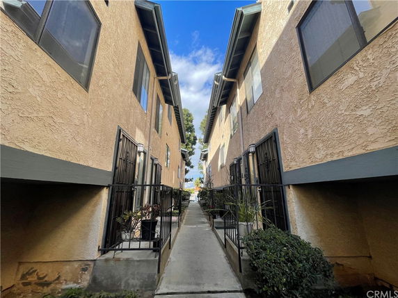 Exterior view of two parallel apartment buildings with a narrow walkway between them.