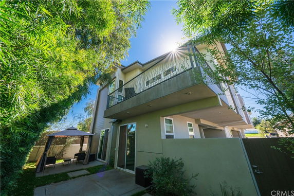 Front view of a multi-story house with a balcony under a sunny sky.