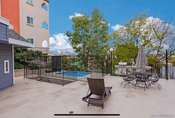Outdoor swimming pool area with lounge chair and dining table.