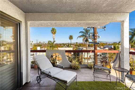 View from a balcony overlooking surrounding area with palm trees and buildings.