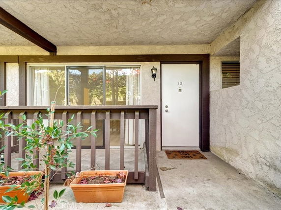 Entrance view of an apartment unit with a white door and sliding glass window.