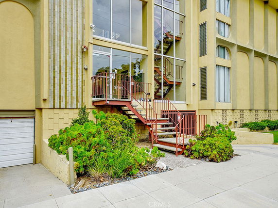 Front view of a multi-story building with an external staircase and large windows.