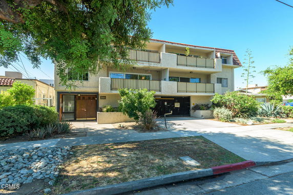 Front view of a multi-story building with balconies and a gated entrance.