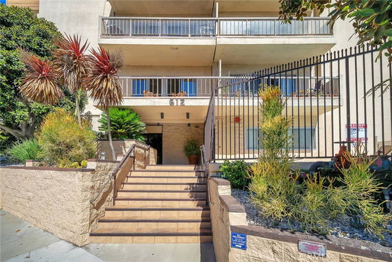 Front view of a multi-story building with balconies and staircase entrance.