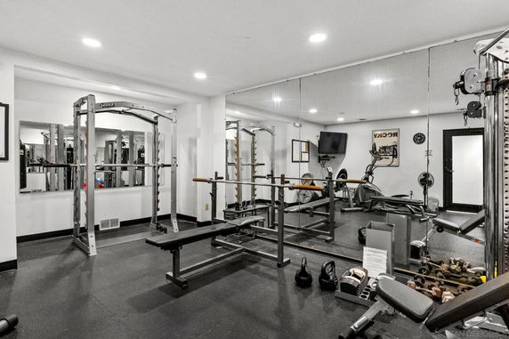 Indoor gym with various exercise equipment and mirrors on the walls.