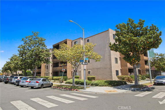Front view of a multi-story apartment building with parking area in front.