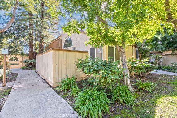 Front view of a house with a wooden fence and large windows, surrounded by trees.