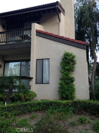 Front view of a two-story house with a balcony and sloped roof.