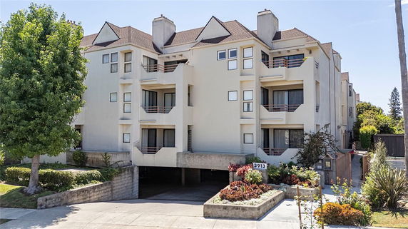 Front view of a multi-story residential building with balconies and a covered parking area.