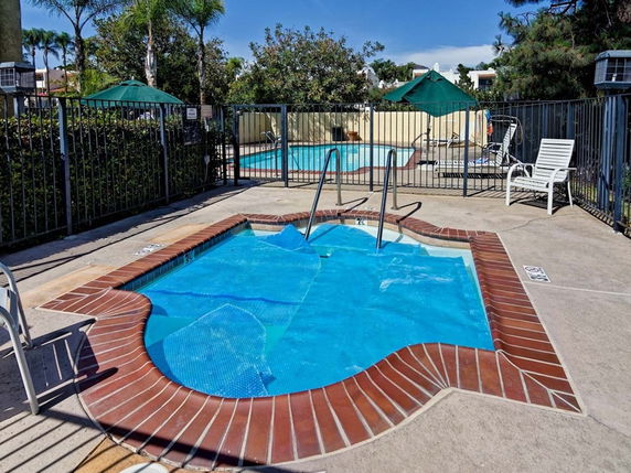 Outdoor swimming pool area with a jacuzzi and lounge chairs.