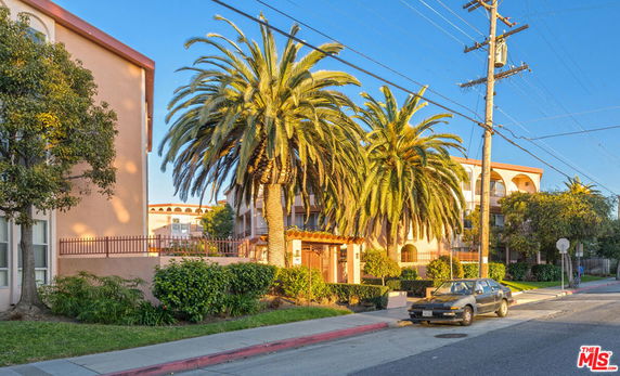Front view of a multi-story residential building with palm trees.