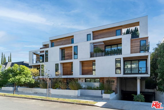 Front view of a modern multi-story apartment building with large windows and balconies.