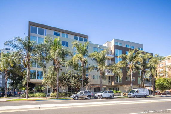 Front view of a multi-story residential building with large windows and balconies.
