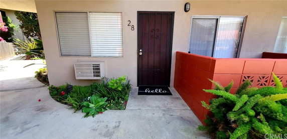 Front view of an apartment entrance with a security door and plants.