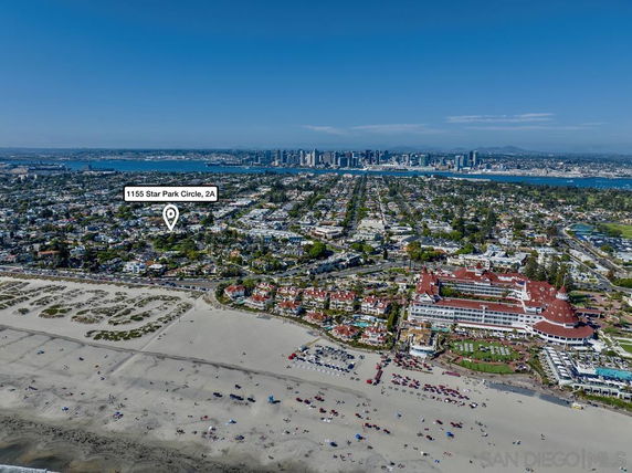 Panoramic view of a coastal city with a beach, residential areas, and a large landmark building.