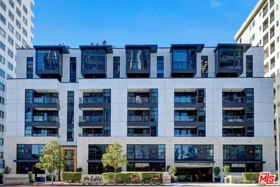 Front view of a multi-story building with balconies and large windows.