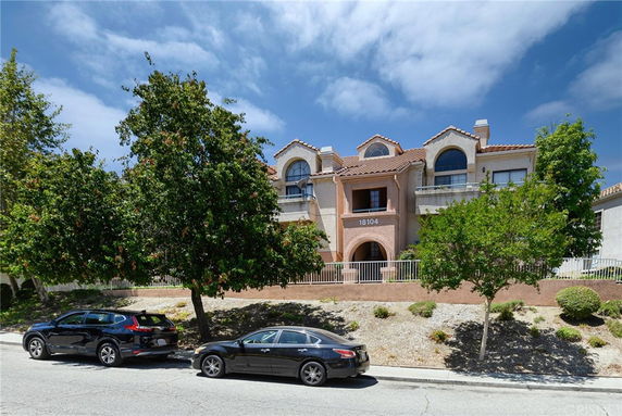 Front view of a multi-story residential building with arched windows and a tiled roof.