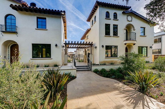 Front view of a two-story house with Mediterranean architectural style and a central walkway.