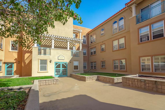 Front view of a multi-story building with beige walls and decorative balconies.
