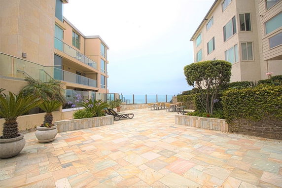 Courtyard area between two residential buildings with seating and ocean view.