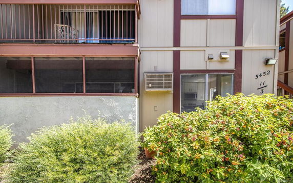 Front view of a residential building with balconies and an air conditioning unit.