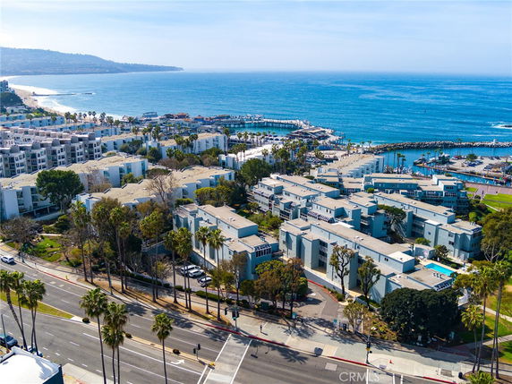 Panoramic view of coastal buildings and a marina by the ocean.