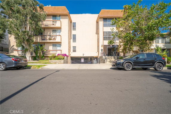 Front view of a multi-story apartment building with a parking entrance.
