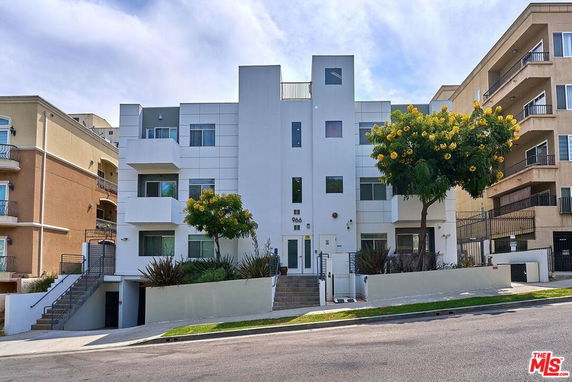Front view of a modern multi-story building with a central entrance and balconies.