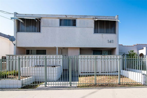 Front view of a two-story building with a metal railing and large windows.