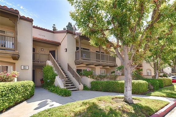 Front view of a two-story apartment building with balconies and staircase access.