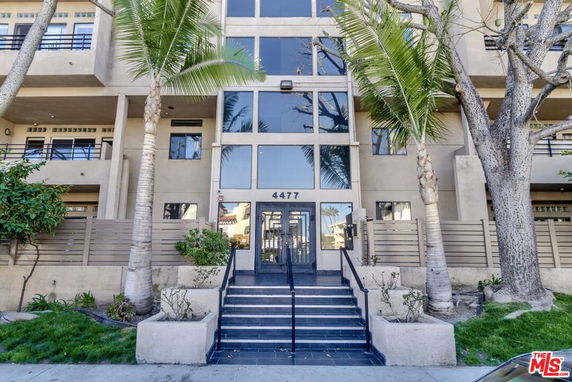 Front view of a multi-story building with glass entrance and balconies.