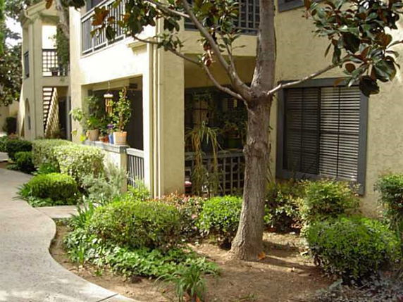 Front view of an apartment building with balconies and landscaped garden.