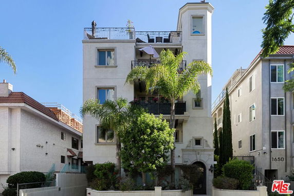 Front view of a multi-story residential building with balconies and a rooftop area.