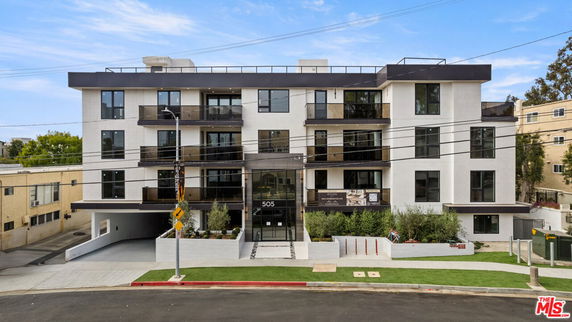 Front view of a modern multi-story apartment building with balconies.