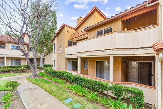 Front view of a two-story residential building with balconies and sliding doors.