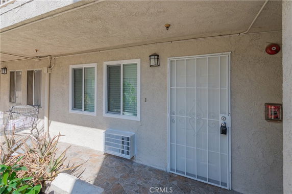 Exterior view of a residential building entrance with windows and a security door.