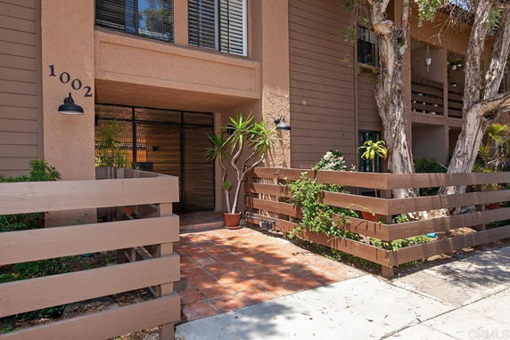 Front view of a residential building with a patio and wooden railing.