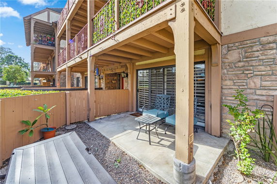 Front view of a multi-story residential building with balconies and a small fenced patio area.