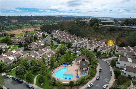 Aerial view of a residential community with multiple buildings, swimming pool, and landscaped areas.