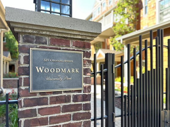 Front view of a multi-story building with a gated entrance and a sign reading 'Woodmark at University Park'.