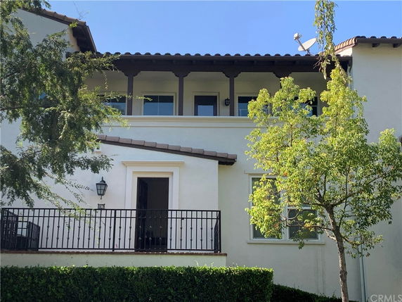Front view of a multi-story house with a balcony and a tiled roof.